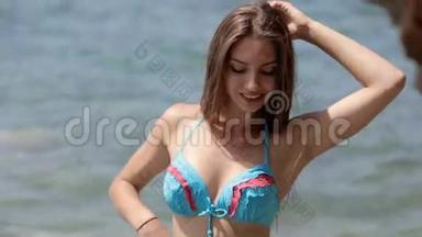 一位留着长发和<strong>比基尼</strong>的年轻<strong>女士</strong>站在岩石海滩上摆姿势